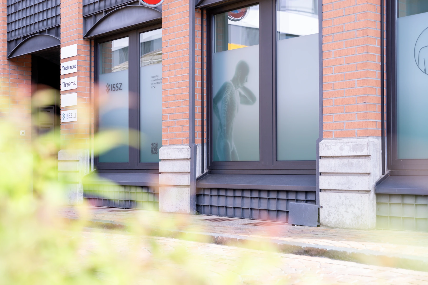 Beschriftete Fensterfront des ISSZ mit Logo und medizinischer Bildwelt